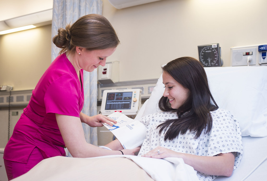 Nurse checking a recovering patient's vitals at the bedside in a recuperative care setting