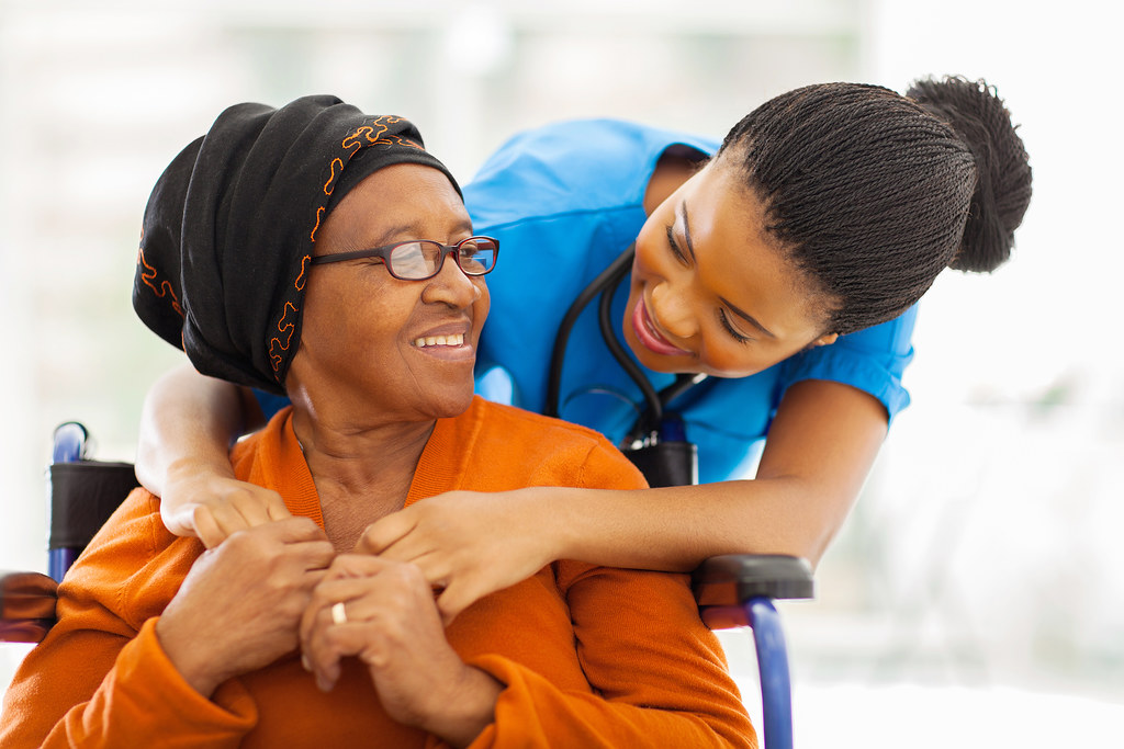 Community health nurse caring warmly for an older patient at a Sacramento-area clinic