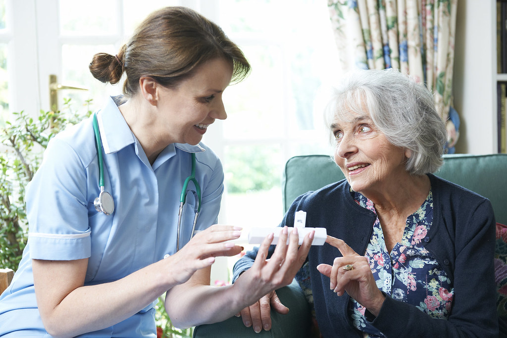 Nurse reviewing medication with a patient, the kind of acuity that requires staffing above the minimum ratio