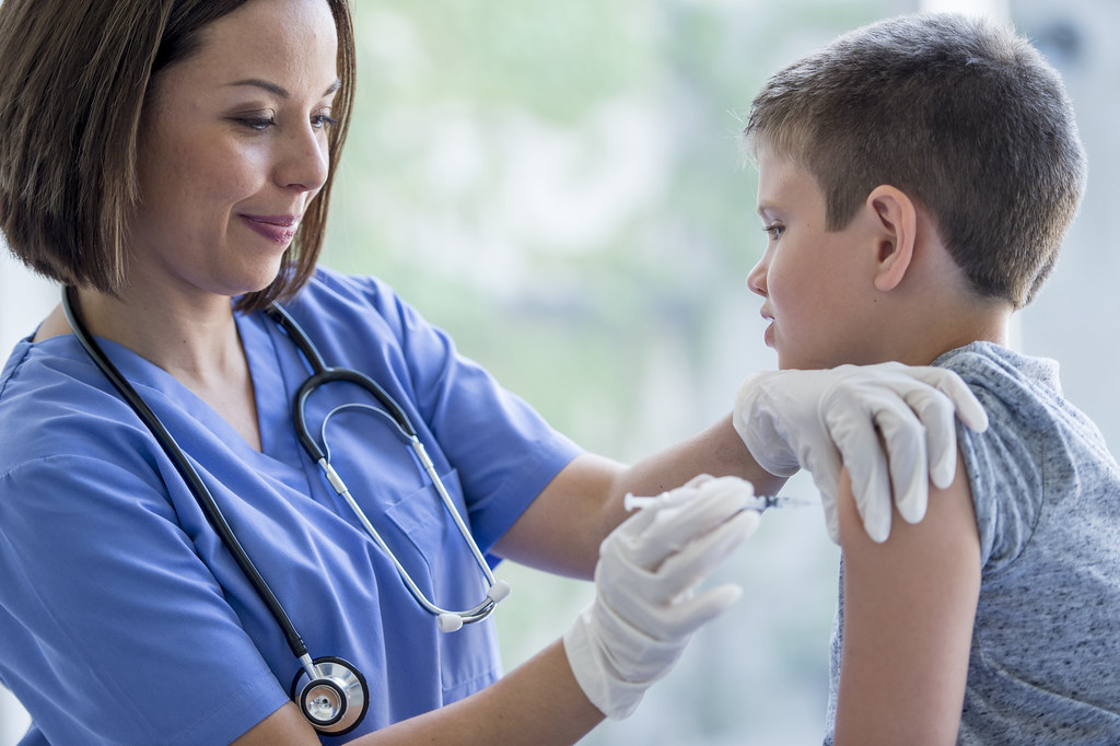 Travel nurse in scrubs caring for a young patient in a California clinic