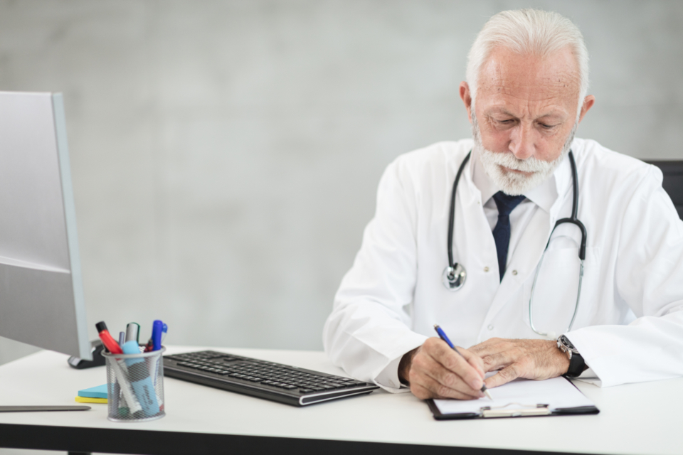 Physician at a clinic desk working through staffing costs and paperwork