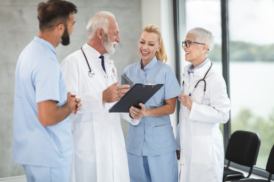 Three clinicians conferring over a tablet in a clinic — the team a permanent hire joins