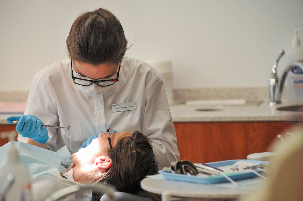 Dental clinician in safety glasses working on a patient's teeth