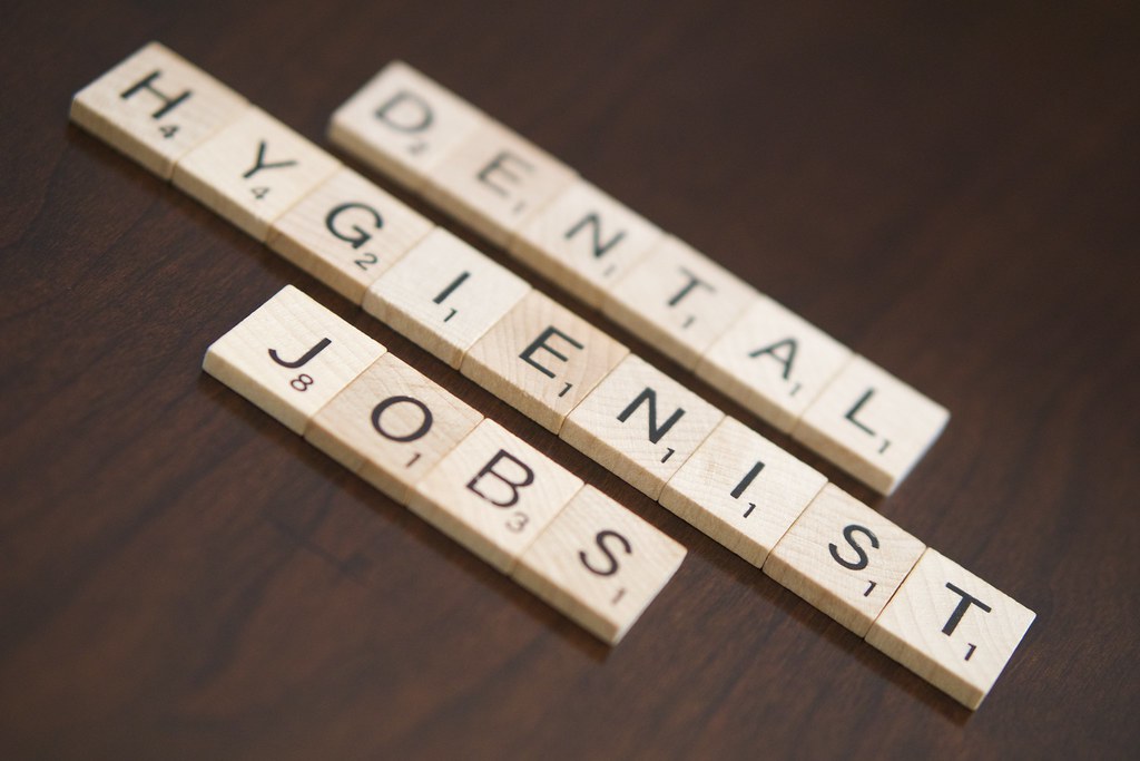 Scrabble tiles spelling out dental hygienist jobs on a wooden table