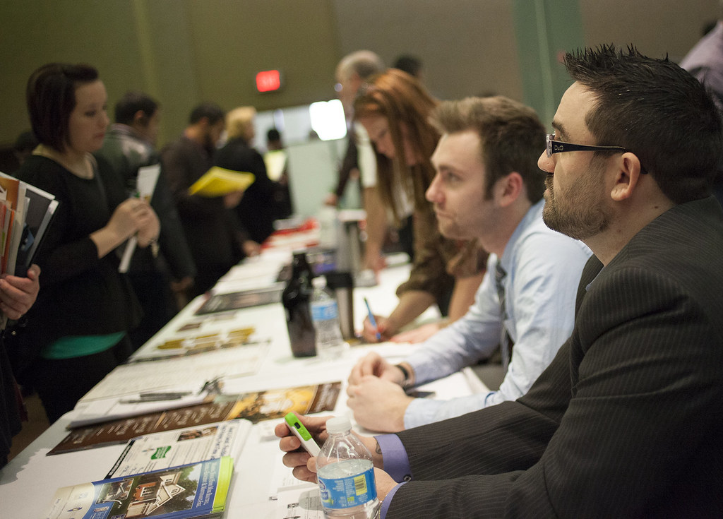 Candidate discussing their resume with recruiters at a healthcare job fair table