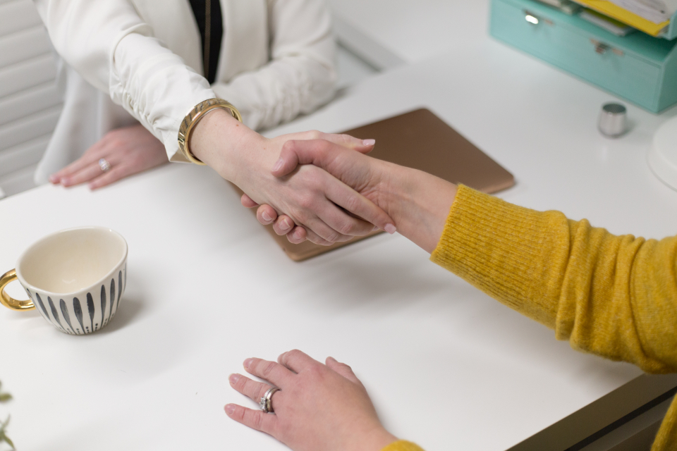 Handshake across a table after agreeing on a temp-to-perm hiring arrangement